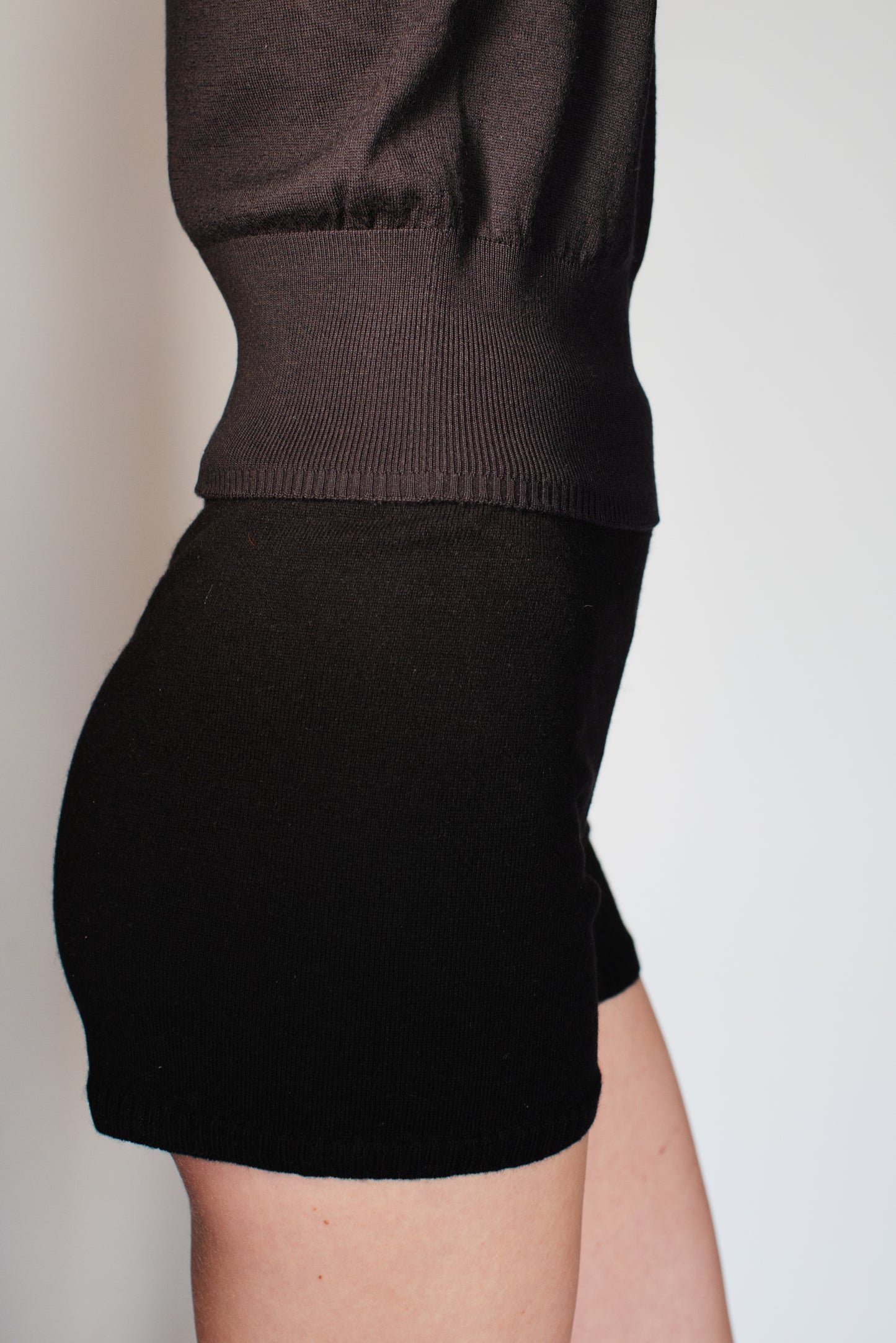 Model wearing the CORINN seamless silk wool knit T-shirt in black styled with matching knit shorts. farbe-schwarz