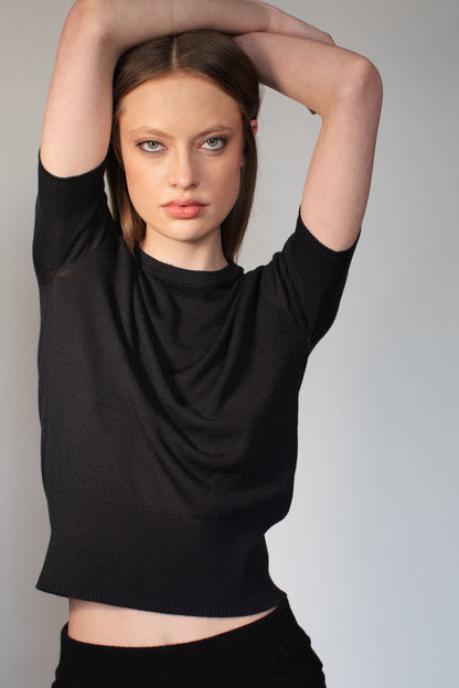 Model wearing the CORINN seamless silk wool knit T-shirt in black featuring a refined minimalist design. farbe-schwarz