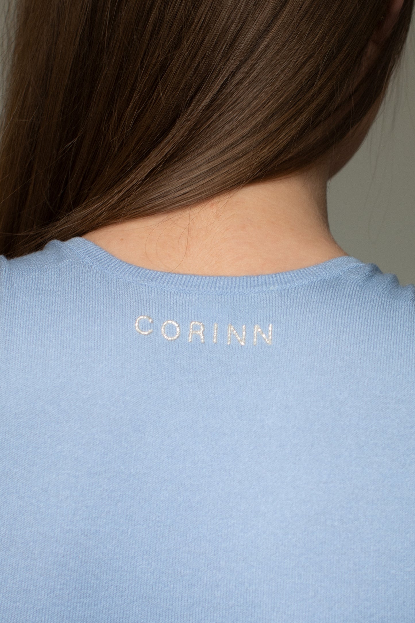 Back detail of sky blue knit bodysuit with subtle CORINN logo embroidery. -farbe-hellblau