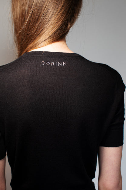 Back view of the CORINN seamless silk wool knit T-shirt in black with discreet CORINN embroidery below the neckline. farbe-schwarz