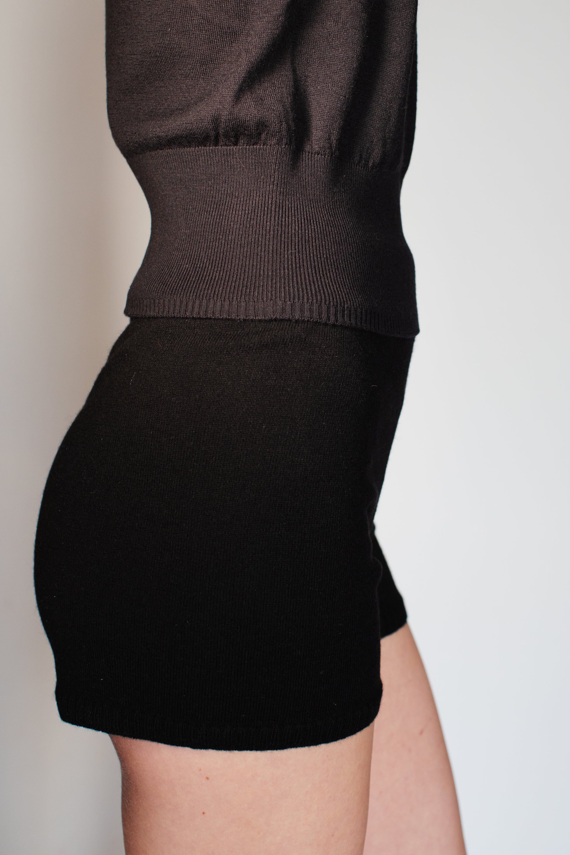 Model wearing the CORINN seamless silk wool knit T-shirt in black styled with matching knit shorts. farbe-schwarz