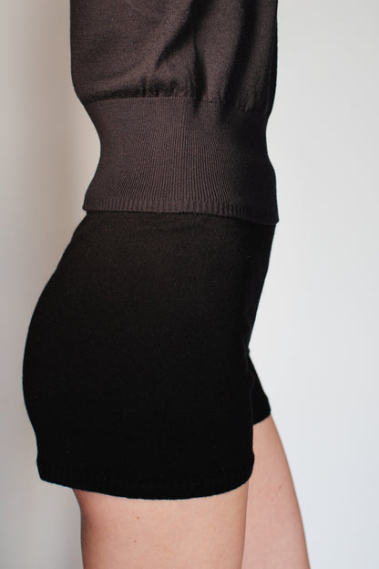 Model wearing the CORINN seamless silk wool knit T-shirt in black styled with matching knit shorts. farbe-schwarz