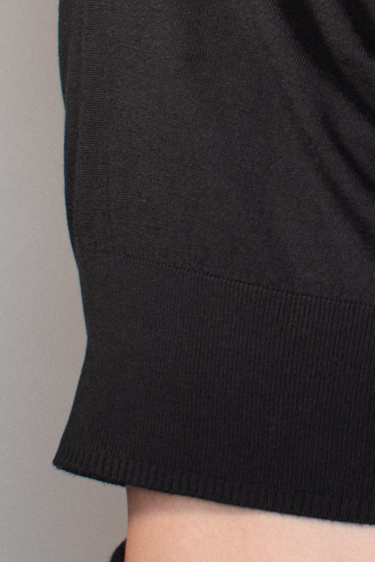 Close-up of the ribbed waistband and seamless construction of the CORINN silk wool knit T-shirt in black. farbe-schwarz
