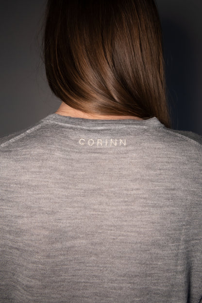 Back view of the CORINN seamless silk wool knit T-shirt in grey featuring subtle CORINN embroidery below the neckline. farbe-grau - melange
