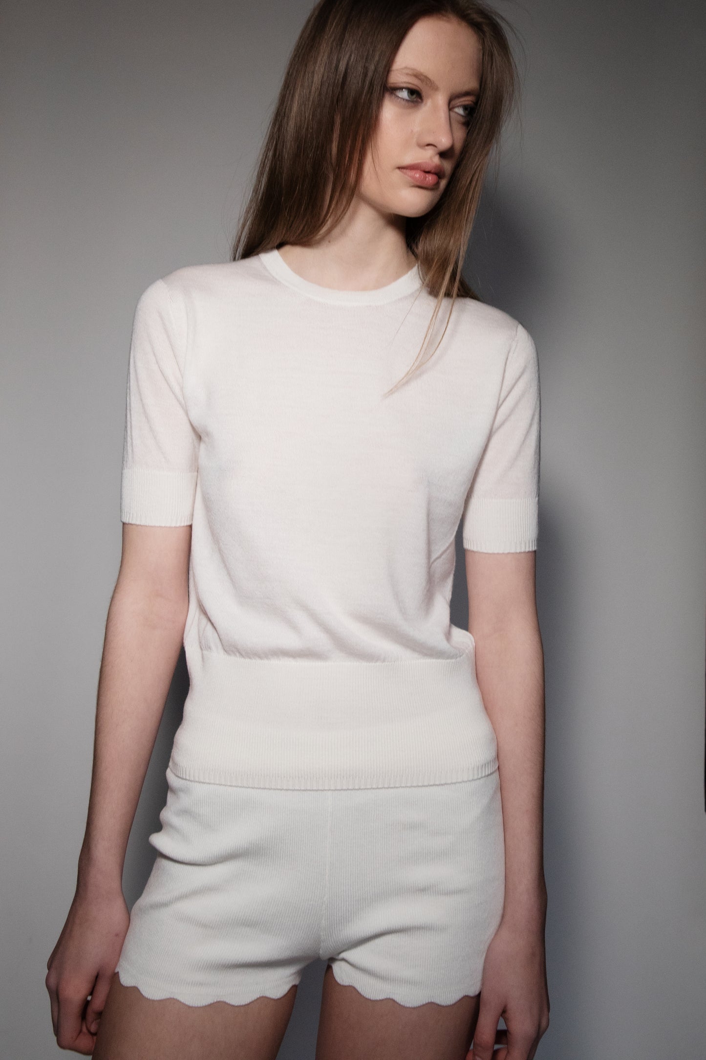 Model wearing the CORINN seamless silk wool knit T-shirt in white with a relaxed fit and minimalist silhouette. farbe-ecru