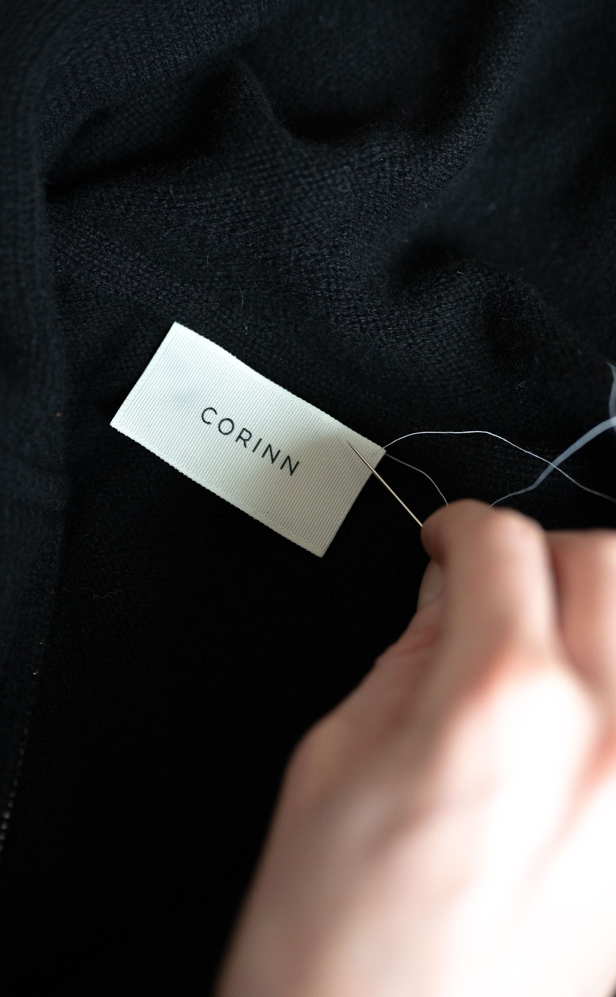 Detail eines schwarzen CORINN Cardigans mit Label